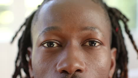 portrait close up of eyes of african american man with dreadlocks smiling in sunny room, slow motion