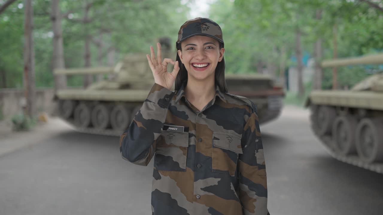 una mujer india feliz, oficial del ejército, mostrando una señal de que está bien.