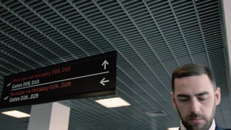 close up view of strict blue-eyed bearded man in pilot uniform in the hall of airport. put on cap on head and smiling. cinematic shot on red camera.