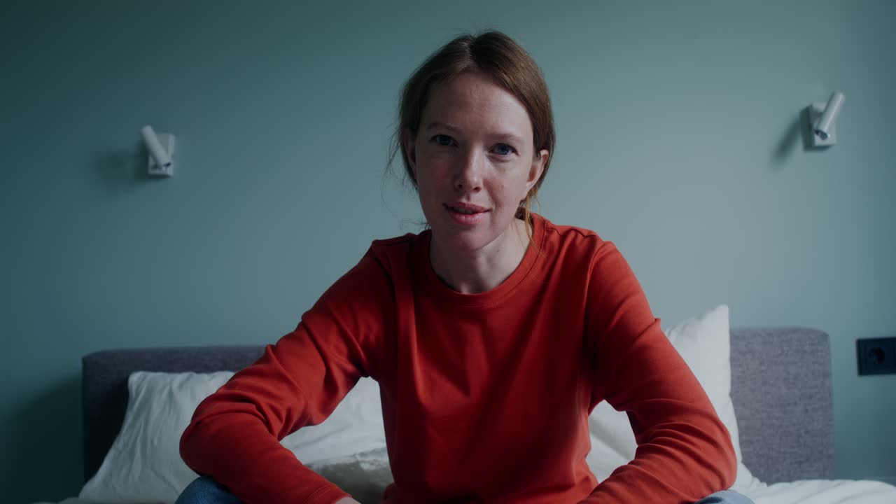 Woman sitting on bed, smiling, video call