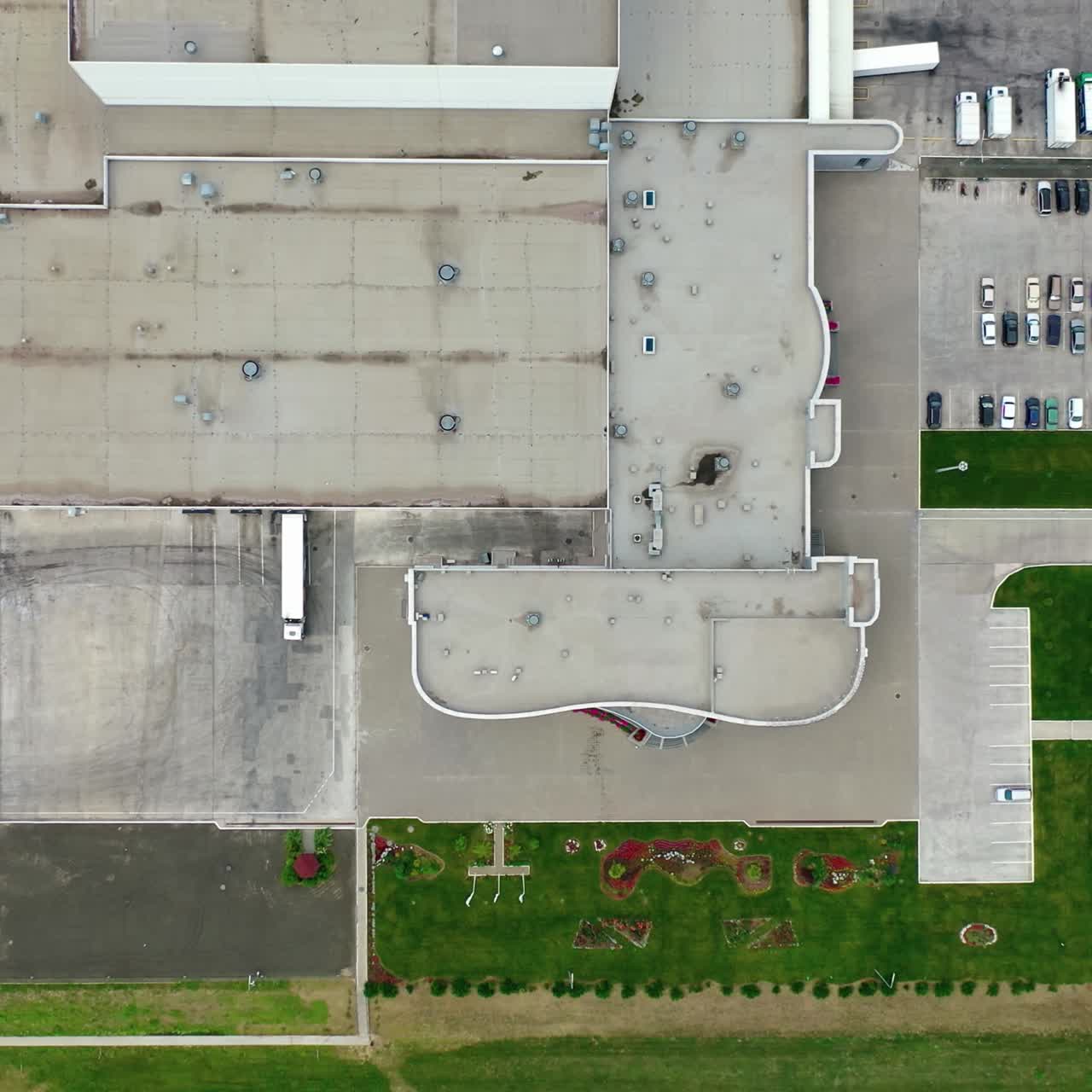 Cars on parking places near the manufacturing. Roofs of industrial buildings of a modern factory on field. Motion camera to the right. Top aerial view