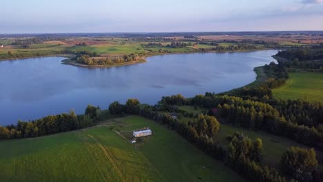 toma aérea de un lago aislado, rodeado de campos y granjas