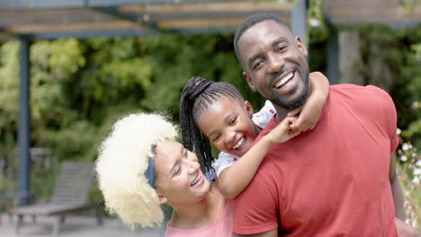 African-American-man-and-biracial-woman-laugh-with-joyful-girl-outdoors