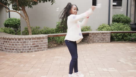 young girl playing outdoors, smiling and enjoying sunny day at school, copy space