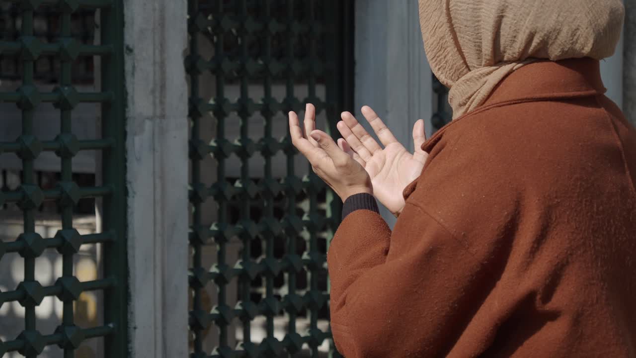 Seorang wanita berhijab sedang salat di masjid.