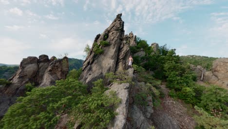 green valley mountain flyover, flying fpv man standing on top of mountain rock, person on top of the world, river danube in background, fast speed aerial shot, cinematic spectaculair sight, austria