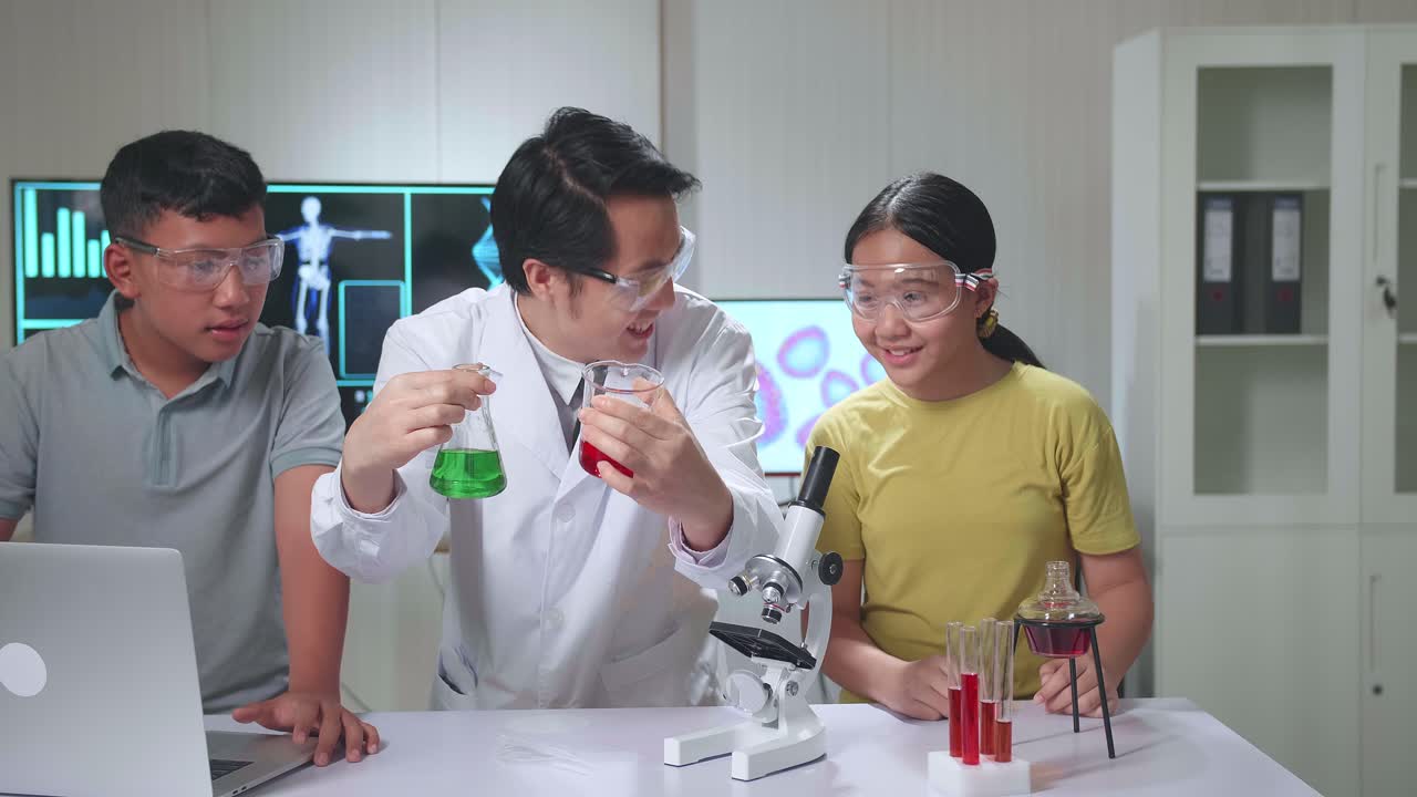 Young Asian Boy And Girl Learning Science Experiment In Laboratory With Teacher In Classroom. Study With Scientific Equipment And Test Tubes