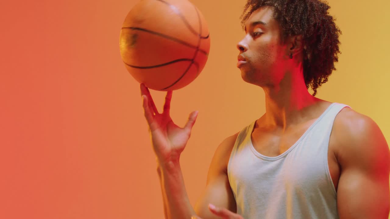 video de un jugador de baloncesto masculino biracial con una pelota en un fondo naranja a amarillo