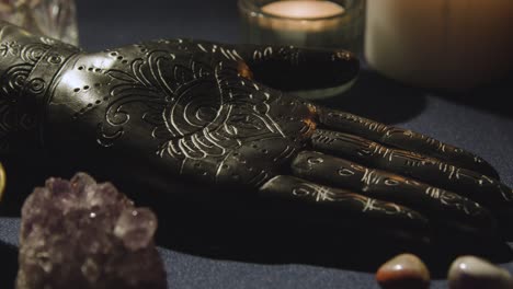 close up of model of hand used in palm reading surrounded by candles and crystals