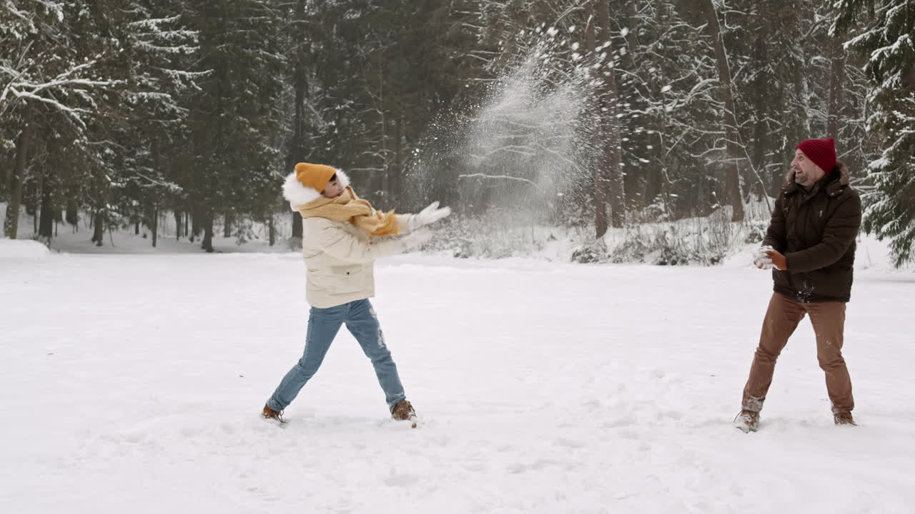 una pareja teniendo una pelea de bolas de nieve en un parque nevado