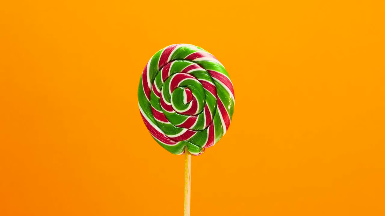 Lecca-lecca su sfondo arancione. Caramella color caramello che ruota.