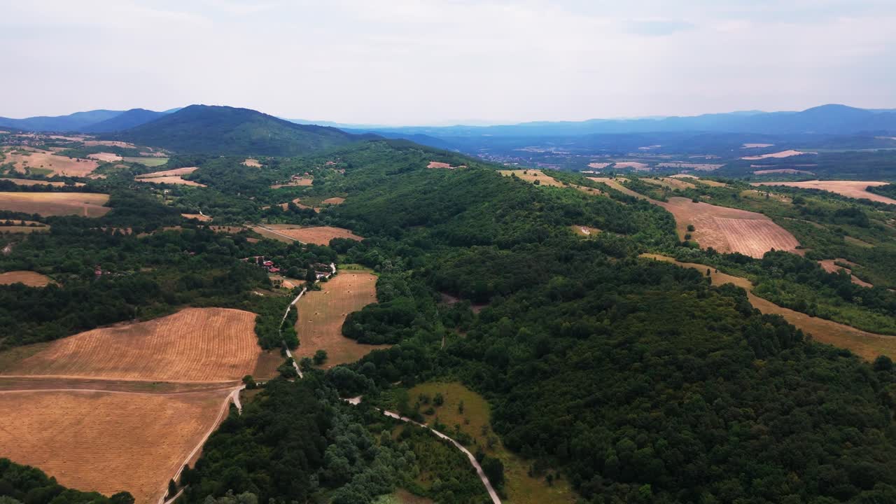 Ampia vista aerea del paesaggio balcanico che mostra foreste fitte, villaggi sparsi, campi aperti e catene montuose distanti