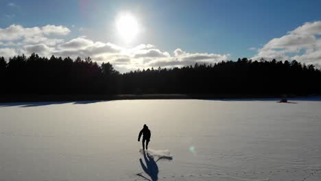 Luftaufnahme-Des-Schlittschuhläufers-Auf-Einem-Schneebedeckten-Zugefrorenen-See-In-Der-Sonne