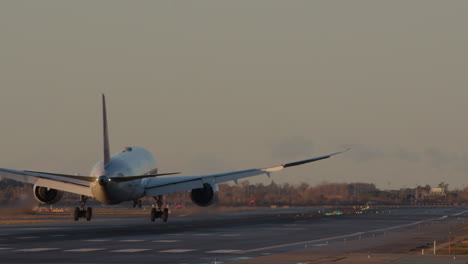 airplane landing on runway at sunset