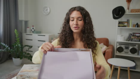 female fashion blogger unboxing and reviewing new shirt on camera at home