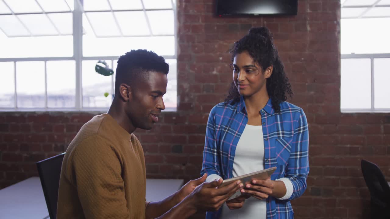 Diverse female and male business colleagues in discussion at work looking at digital tablet