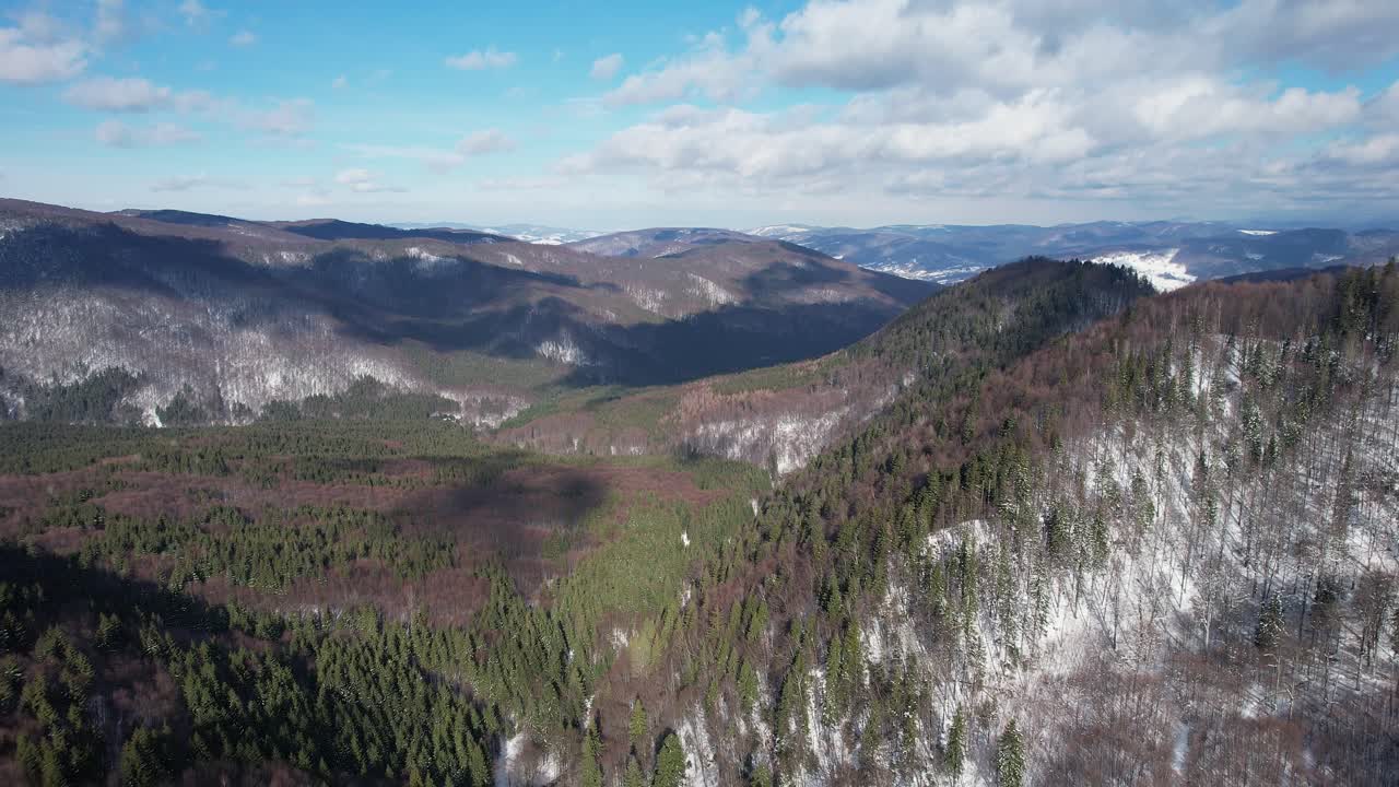 montañas siriu con manchas nevadas y bosques exuberantes bajo un cielo azul, vista aérea