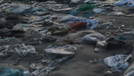 Drone-shot-revealing-plastic-waste-on-the-beach-shore,-Water-pollution,-Fashion-Waste,-Ocean-garbage-with-the-view-of-the-beach-under-foggy-sky