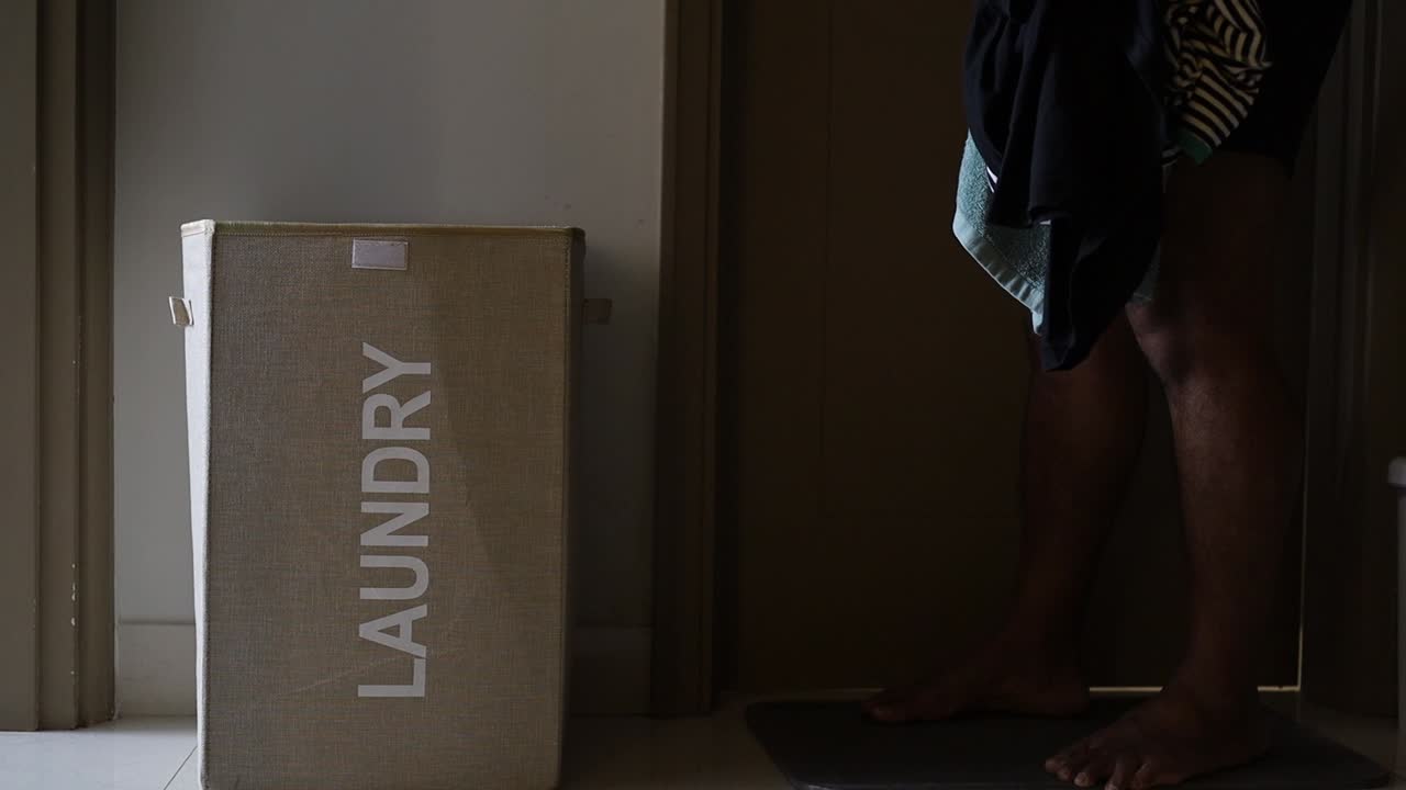 A Man puts dirty clothes in the laundry basket in the hotel room