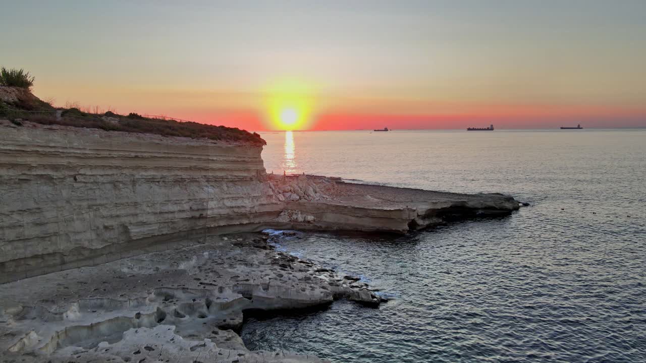 Auringonlasku St. Peter’s Poolin yllä, jossa on kerrokselliset kalkkikivikalliot ja tyyni Välimeri