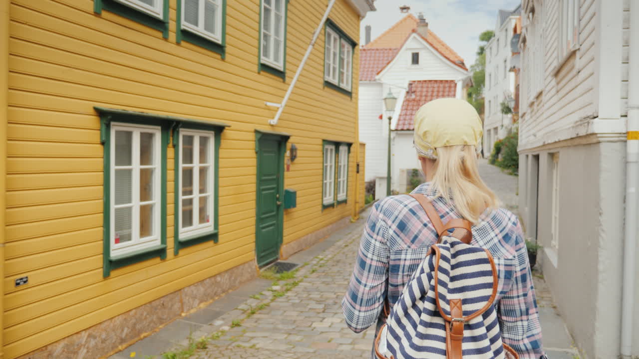 한 여성이 오래된 도시의 좁은 길을 따라 걷고 있다. 스마트폰에서 내비게이터를 사용한다.