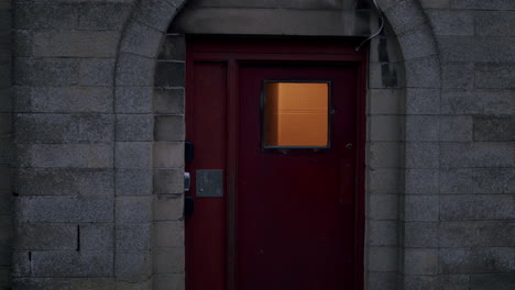 Puerta-De-Entrada-De-Metal-Rojo-En-Una-Casa-De-Bloques-De-Cemento-Con-Un-Aspecto-Cinematográfico-Cambiante