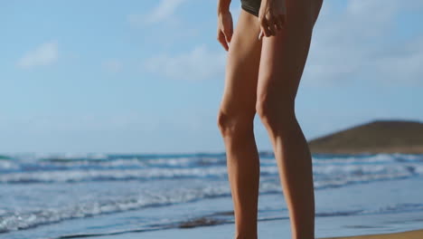 fitness young woman working out core and glutes with bodyweight workout doing squat exercises on beach. sporty girl squatting legs as part of an active and fit life. stedicam shoot