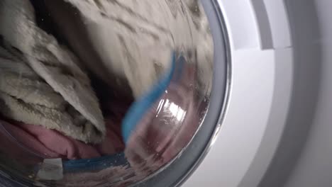 Laundry-going-round-in-a-washing-machine-medium-shot