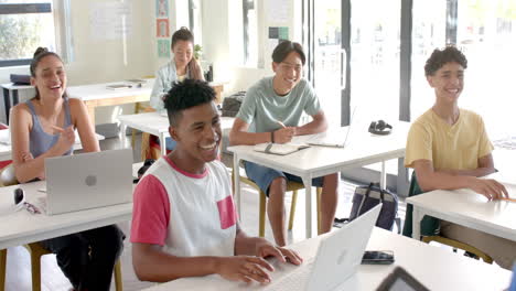 in high school, teenagers using laptops and smiling in classroom, enjoying lesson