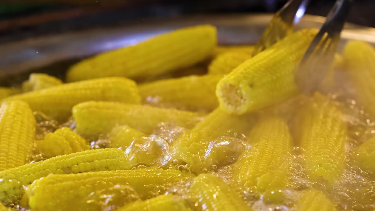 maíz hirviendo en una olla grande con pinzas