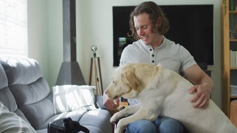 Feliz-Hombre-Discapacitado-Caucásico-En-Silla-De-Ruedas-Jugando-Con-Un-Perro-Mascota-En-La-Sala-De-Estar