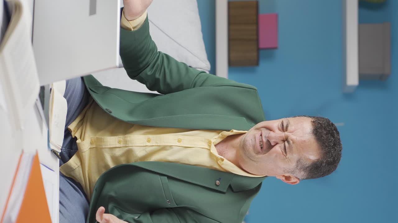 video vertical de un trabajador de oficina en casa, un anciano trabajando en una computadora portátil estresado.