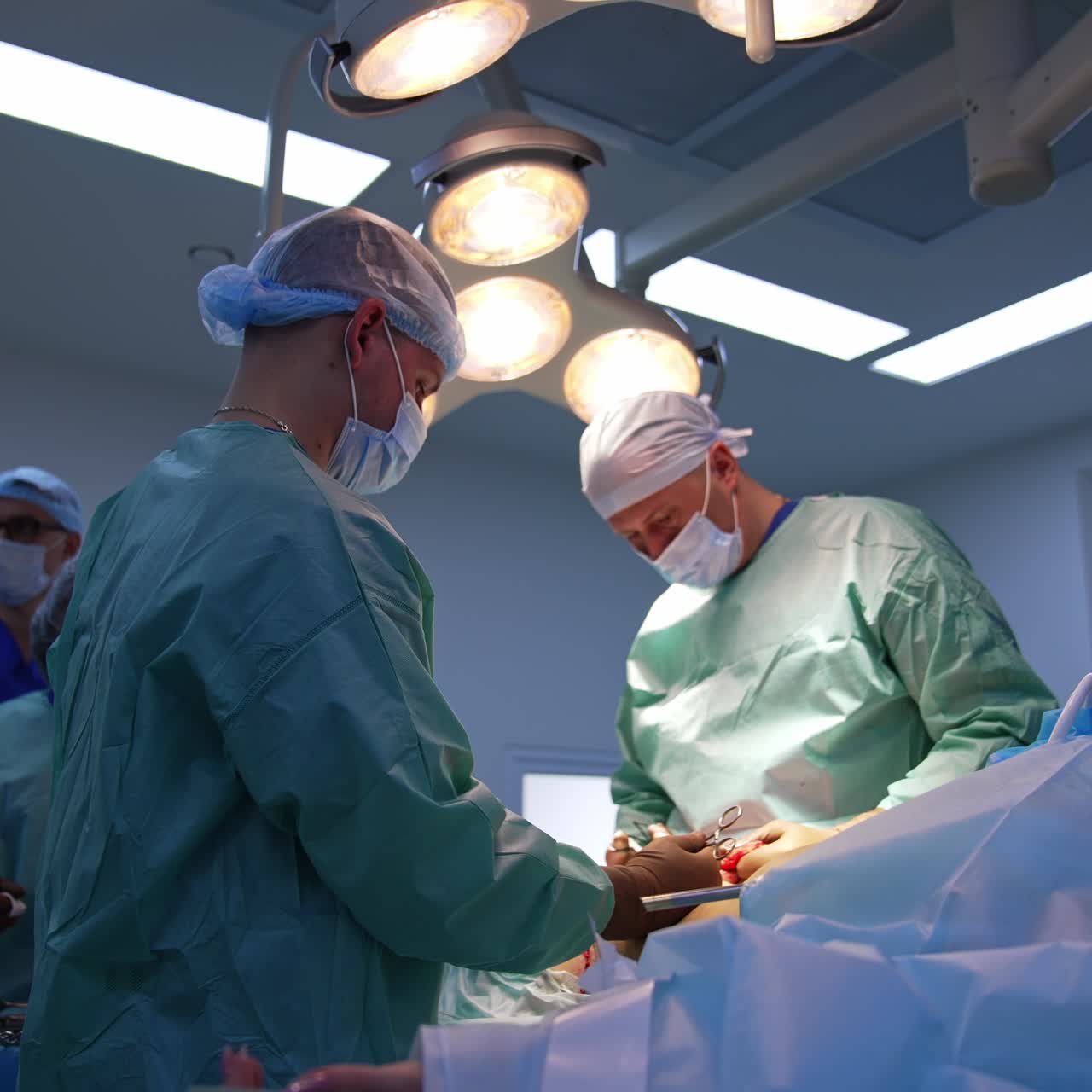 Leading surgeon and his assistant conducting plastic surgery in modern clinics. Medical staff at backdrop. Low angle view