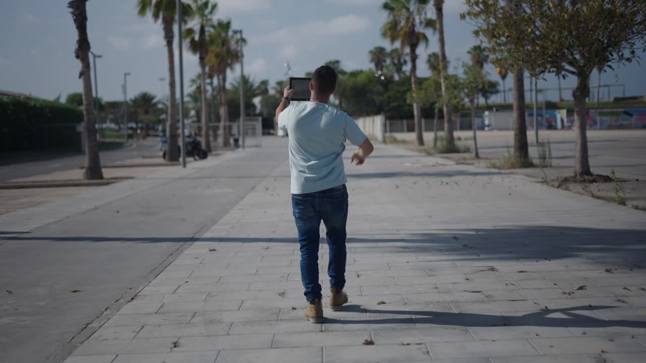 Man walking outdoors with a tablet