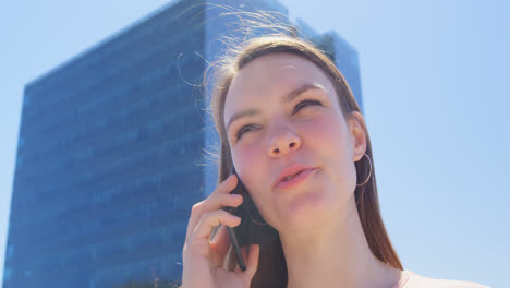 Low-Angle-Ansicht-Einer-Jungen-Kaukasischen-Geschäftsfrau,-Die-Auf-Dem-Bürobalkon-Mit-Einem-Mobiltelefon-Spricht,-4K