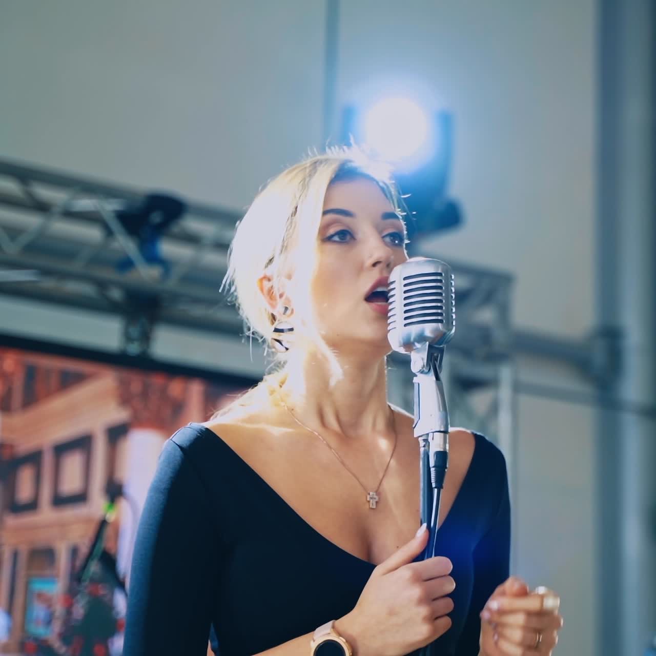 Attractive woman singing into a mic. Professional singer standing at the microphone and performing a live music. Slow motion.
