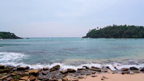 ocean view of surfers waiting the next waves at hiriketiya beach in sri lanka