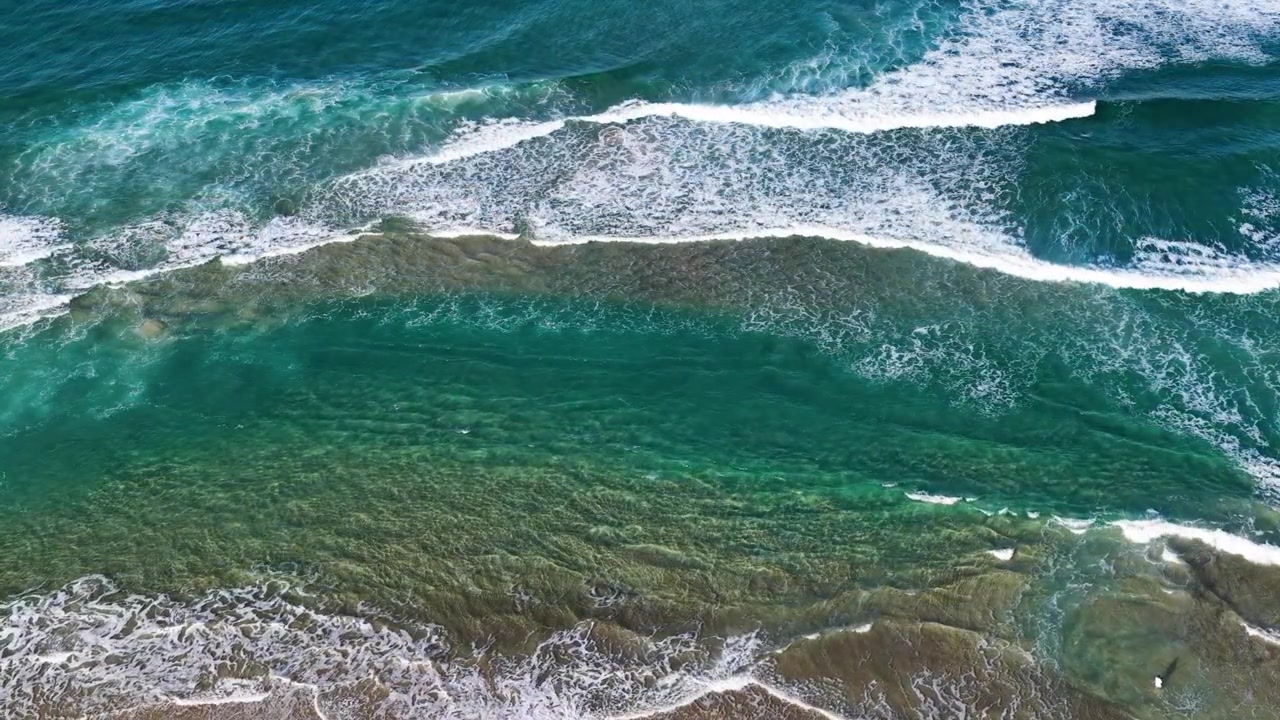 Vista aerea dall'alto di onde oceaniche turchesi che si infrangono vicino all'isola di South Stradbroke, Australia