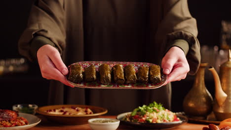 woman serving stuffed grape leaves