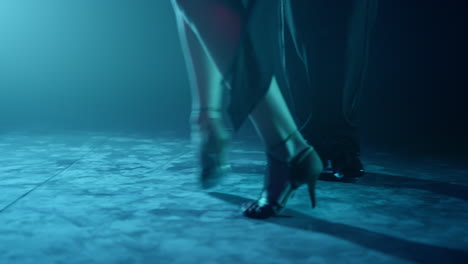 couple legs dancing tango on stage. dancers feet performing latin dance in dark.