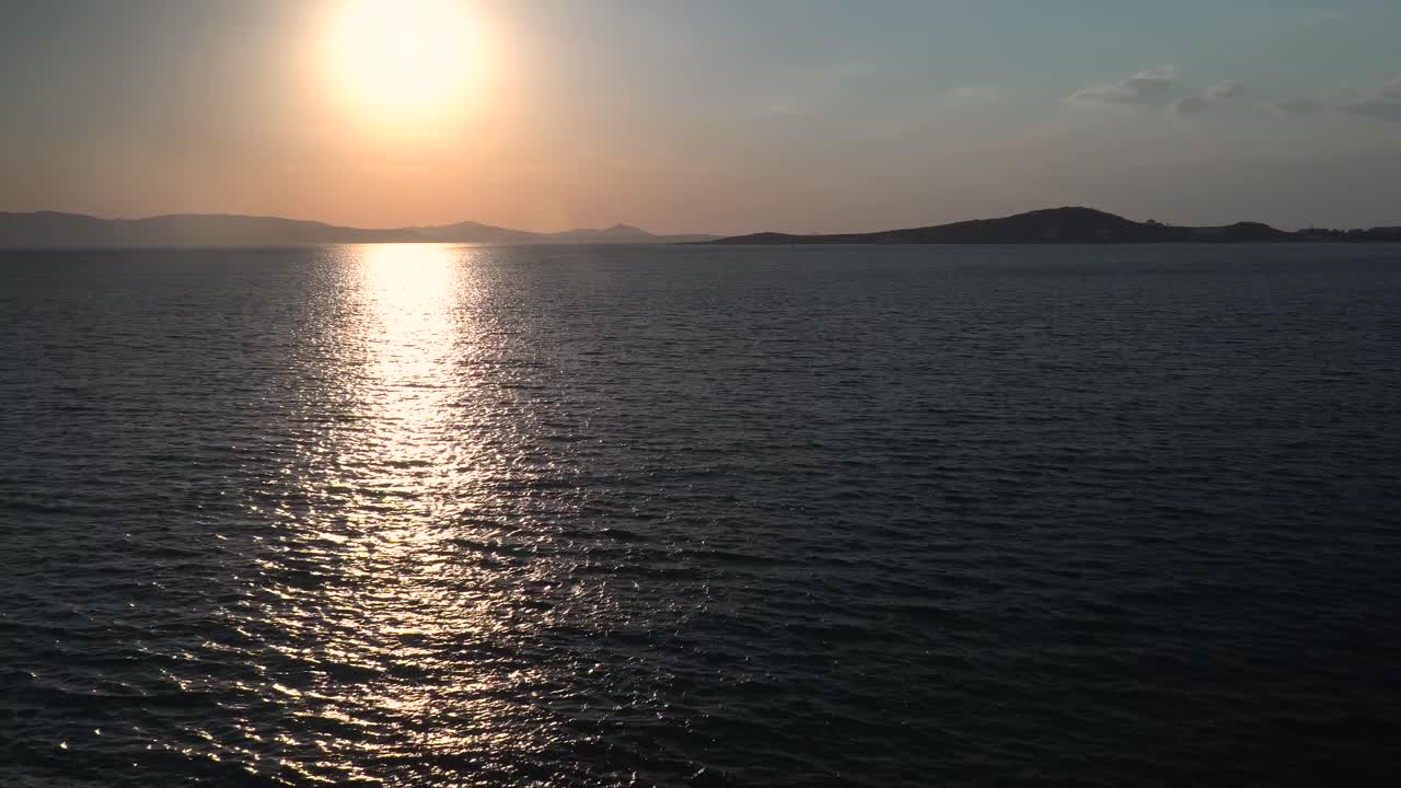 멀리 있는 반사와 섬이 있는 바다 위의 낮은 석양