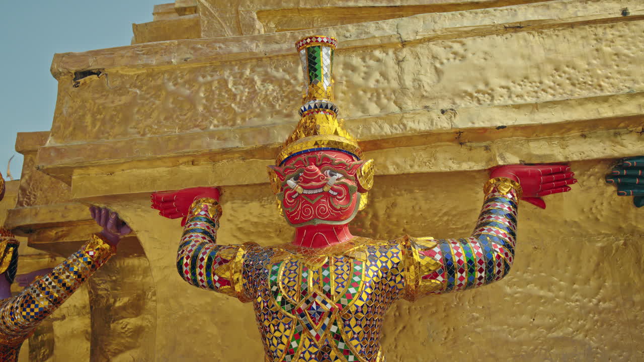 バンコクのワット・プラケオにある金色のチェディを支える色鮮やかな守護鬼像、タイの伝統的な寺院芸術