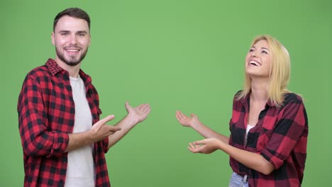 young happy couple showing something together