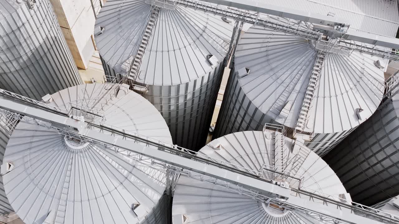 Aerial rotation over shiny silver silos at Dobele grain, flour processing site