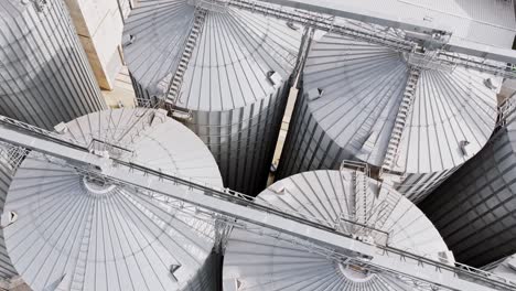 aerial rotation over shiny silver silos at dobele grain, flour processing site