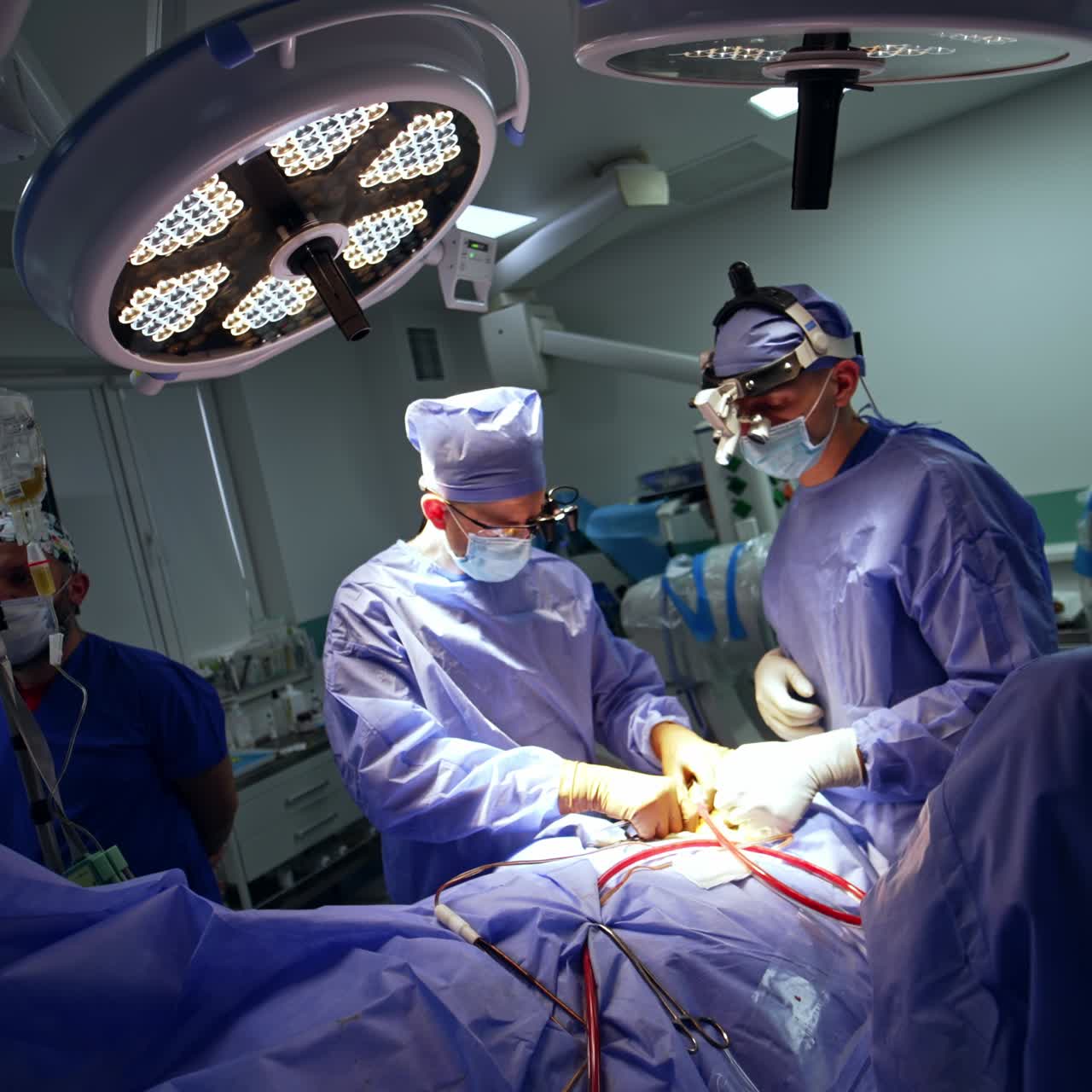 Team of professional neurosurgeons perform procedure at modern surgical room. Two surgeons wearing headlights cooperate at operation