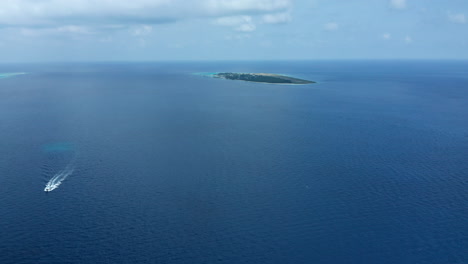 aerial view of a crossing boat with island dharavandhoo in the background, the maldives.