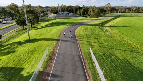 aerial view of cyclists riding on a winding track surrounded by lush greenery, captured during golden hour lighting
