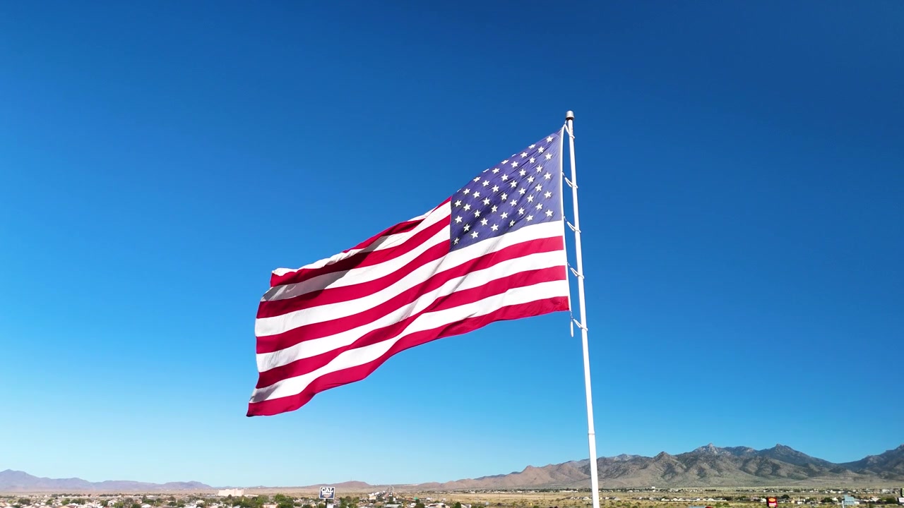 Cinematic stock footage of the American flag waving proudly in the strong wind under bright sunlight. High quality b-roll for patriotic and commercial projects