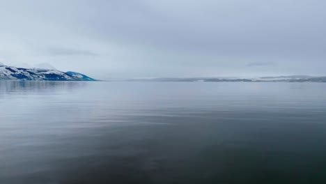 Close-up-in-movement-of-a-Patagonian-lake,-its-crystal-clear-waters-shimmering-in-the-winter-sunlight